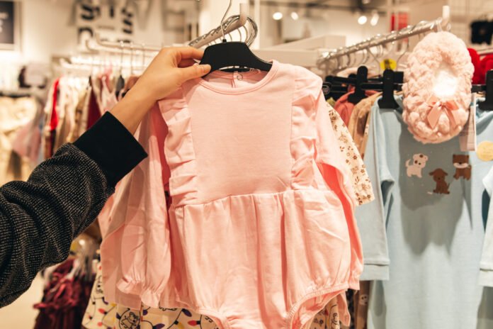 Little pink dress in baby store. Mother doing shopping in baby shop.